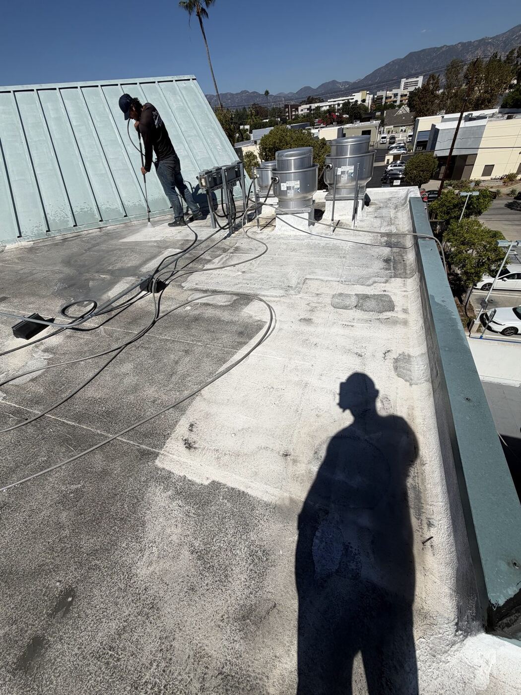 Foothill crew member cleaning a commercial flat roof with a pressure washer