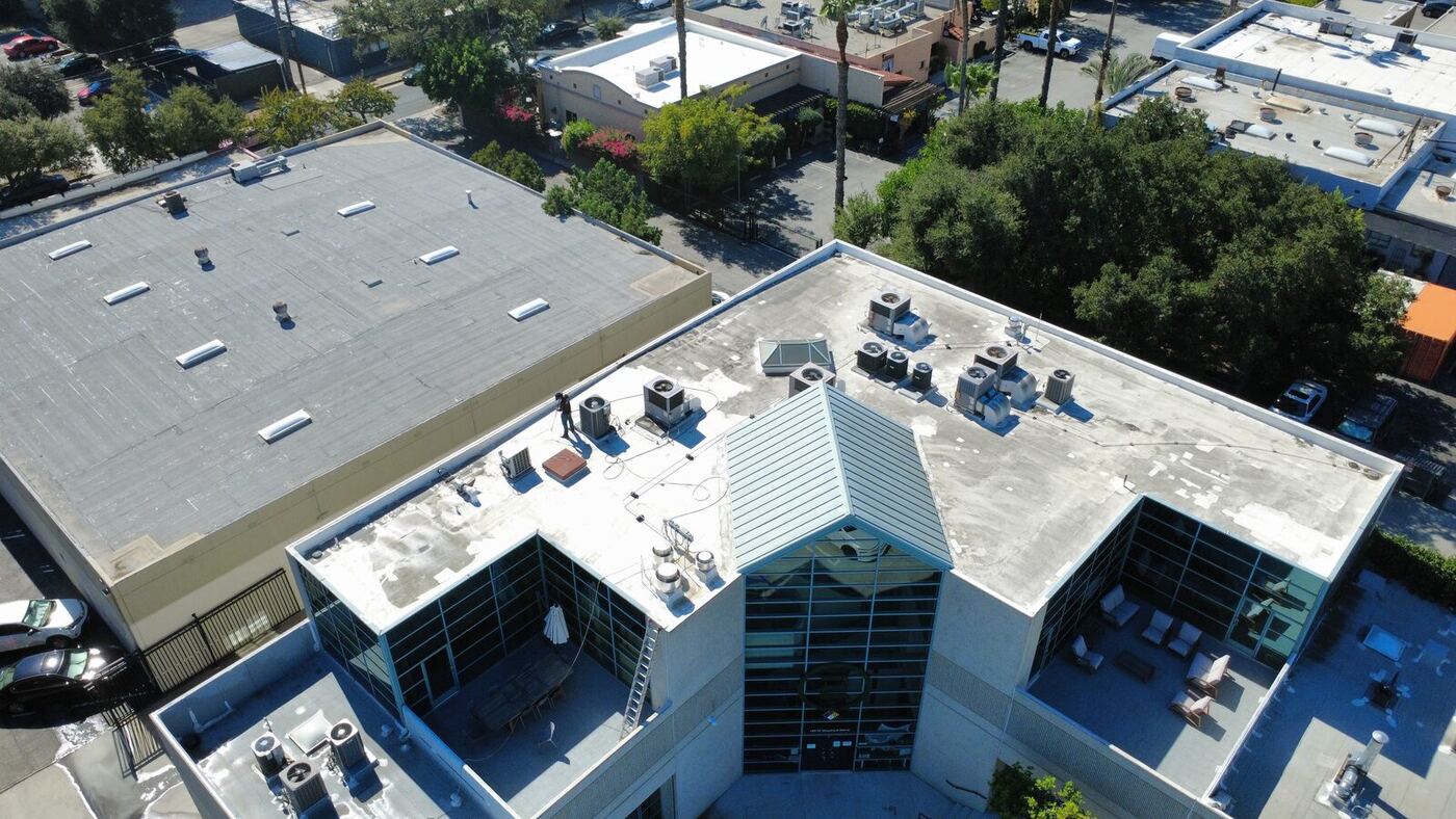 Aerial view of a commercial building with a white TPO flat roof