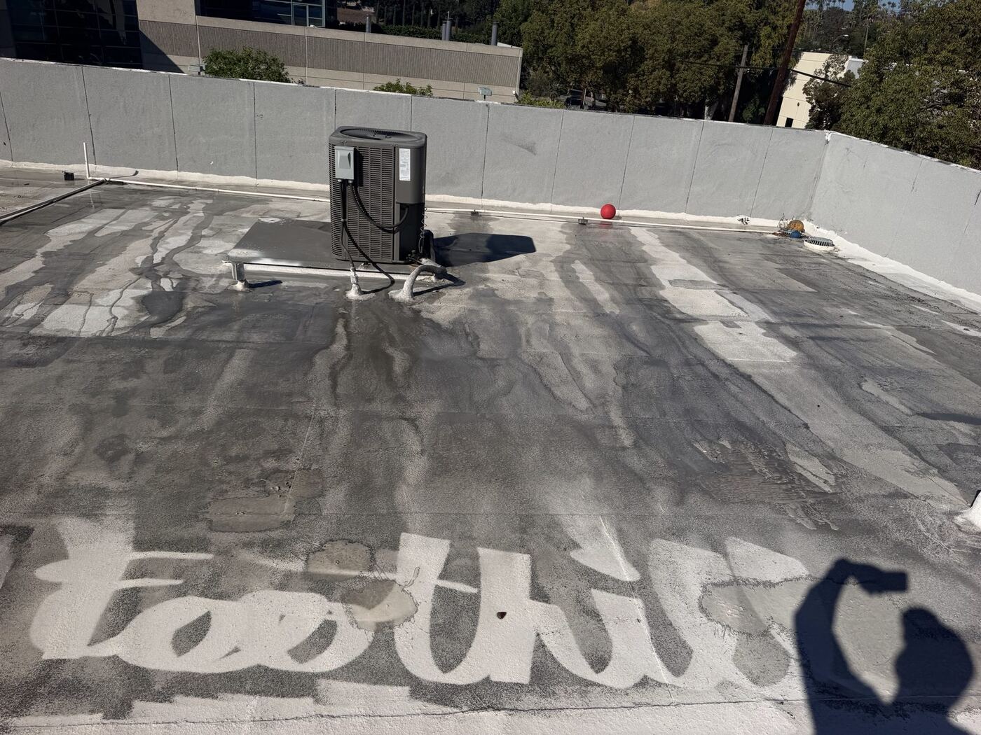 Foothill written in the clean white strip of a dirty TPO roof during water-only cleaning